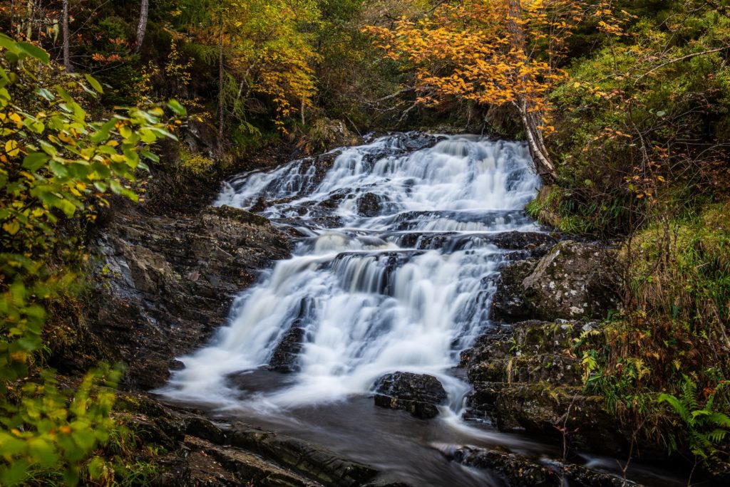 Small waterfalls on the Allt na Bodachan burn above the main drop at Plodda Falls in Glen Affric with the autumn colours in the trees